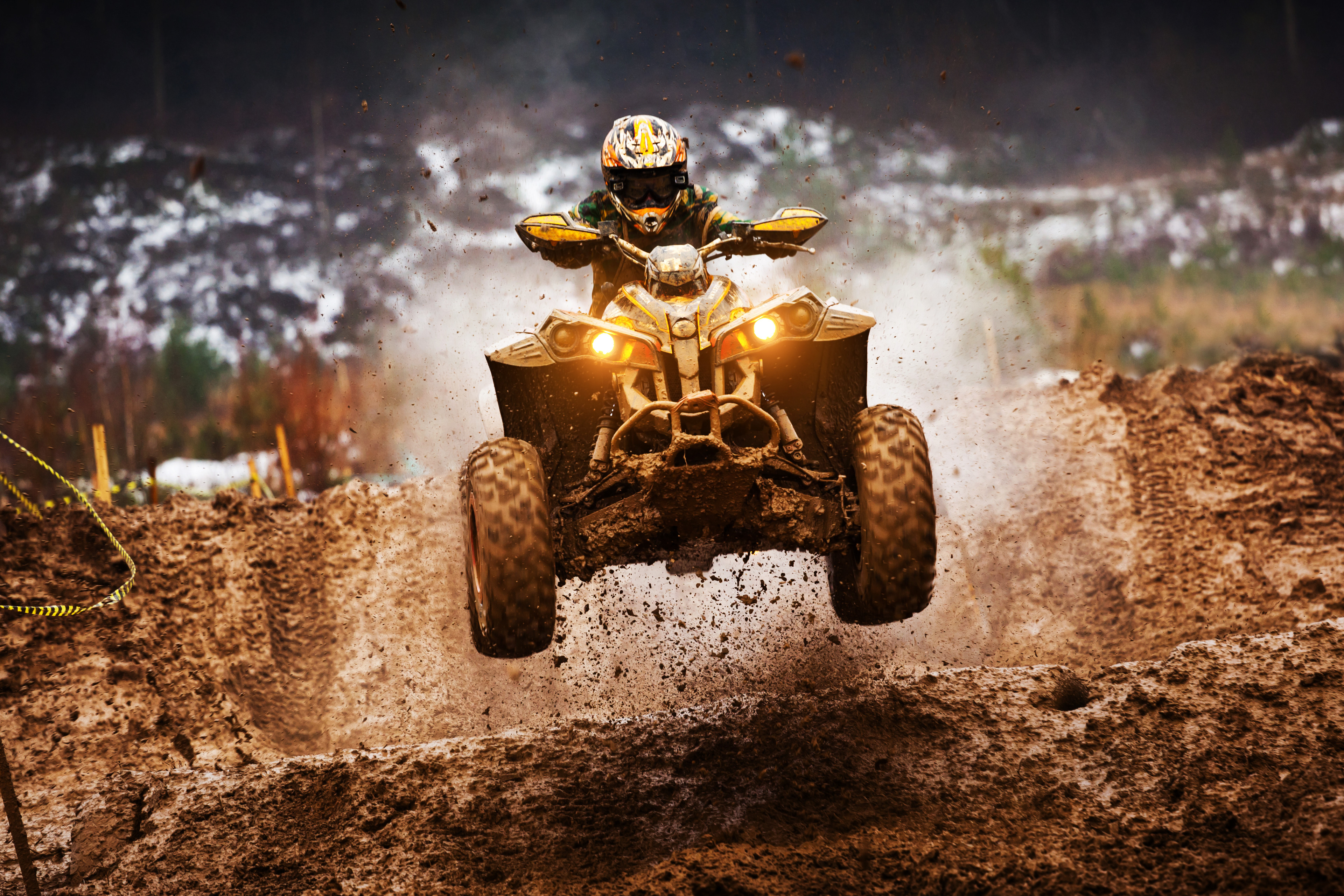 Person on quad-bike going over a muddy jump