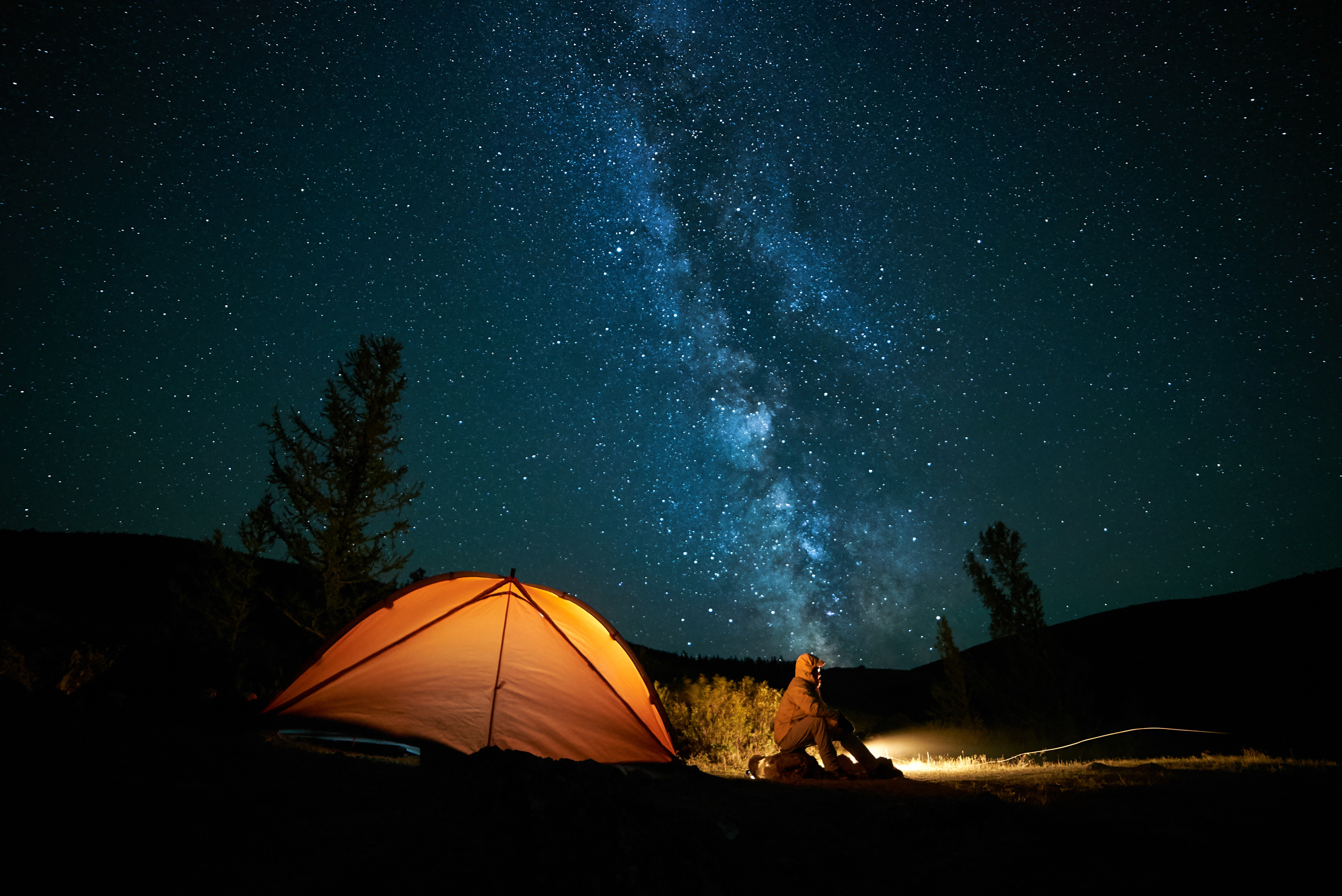 Person camping under a starry sky.